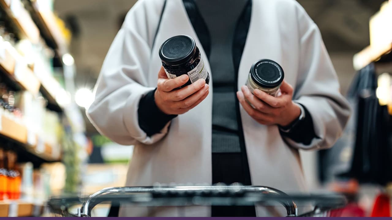 Shopper comparing supplement jars in grocery store aisle aisle