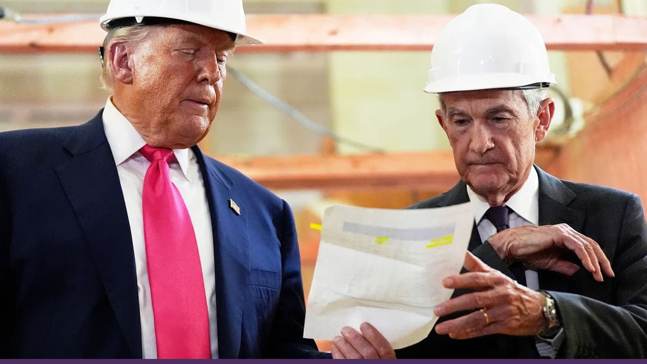 Two men wearing white hard hats review a document together at a construction site, with one pointing to details on the paper.