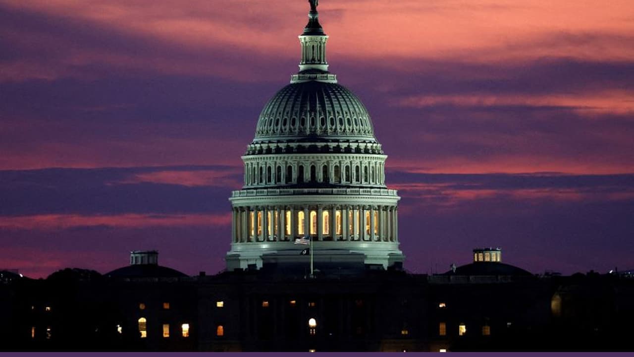 US Capitol building illuminated against purple sunset sky
