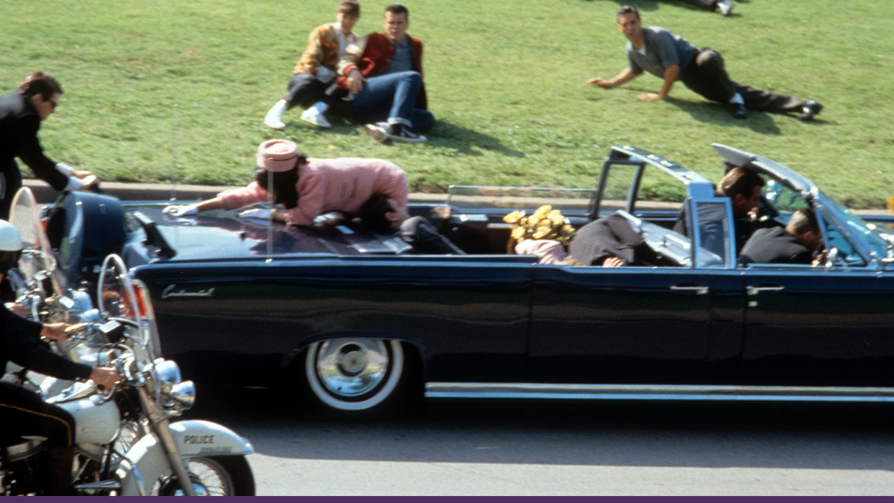 The presidential motorcade in Dallas at the moment of the assassination of President John F. Kennedy, with First Lady Jacqueline Kennedy climbing onto the trunk of the car.